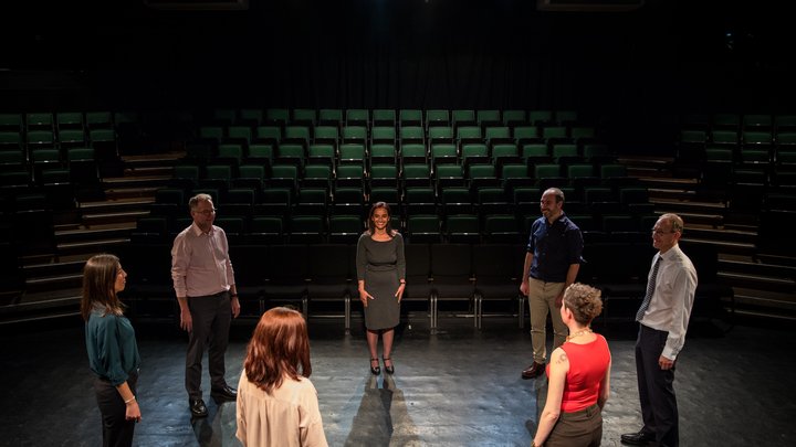 A RADA Business tutor and participants take warm-up in a theatre auditorium.